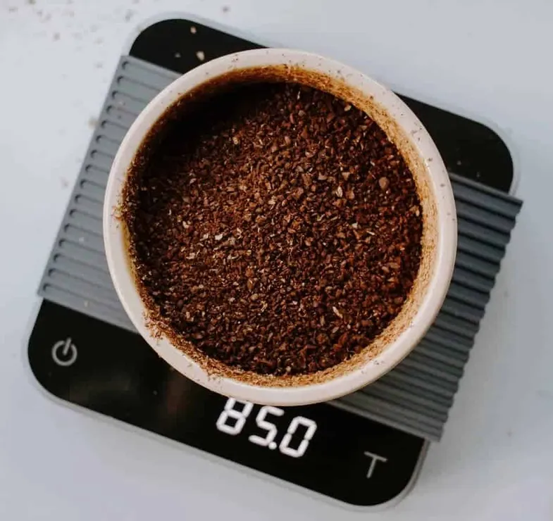 Café molido grueso que se pesa en una balanza